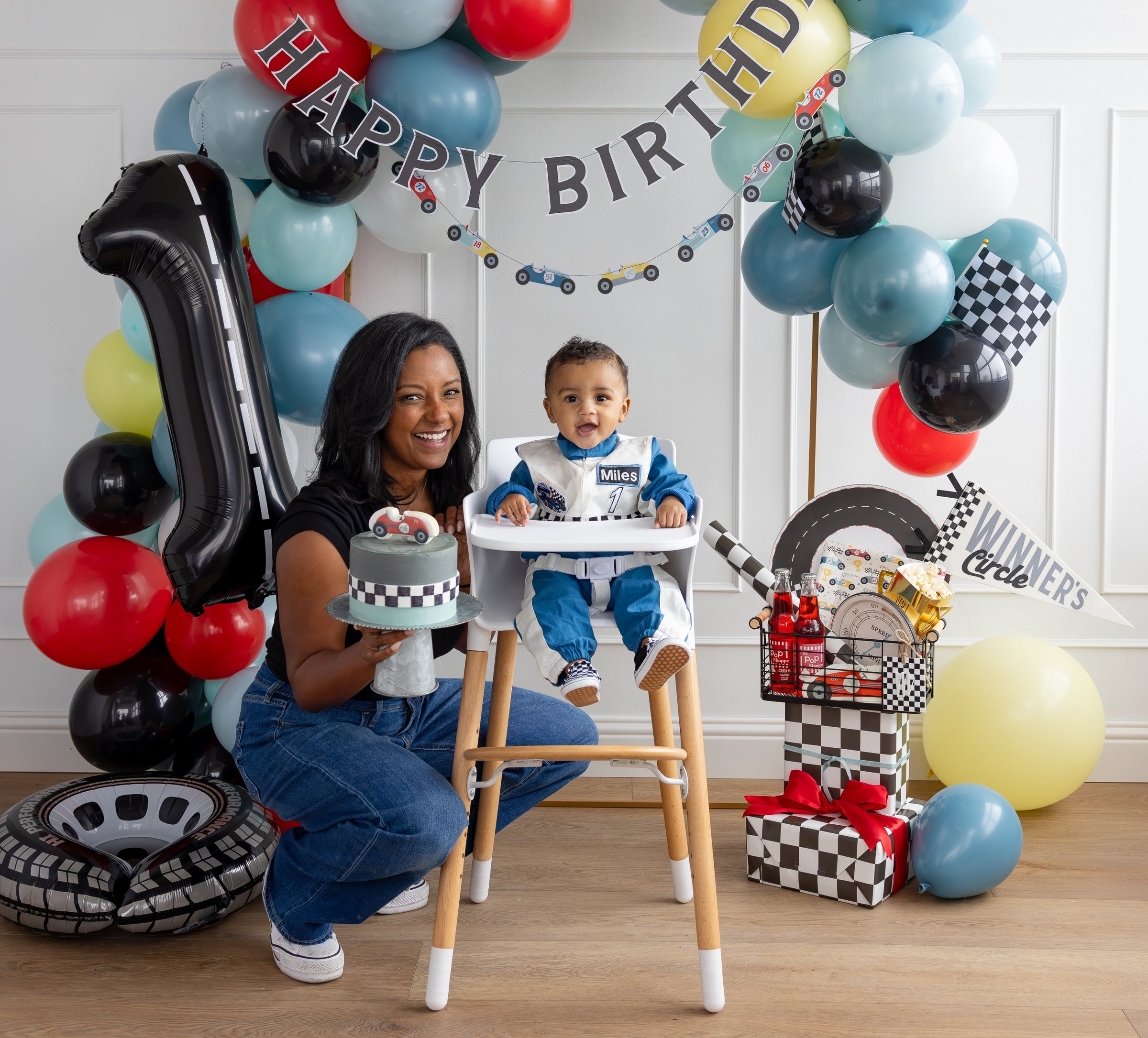 Race car birthday party setup with checkered flags and a blue red and yellow balloon arch