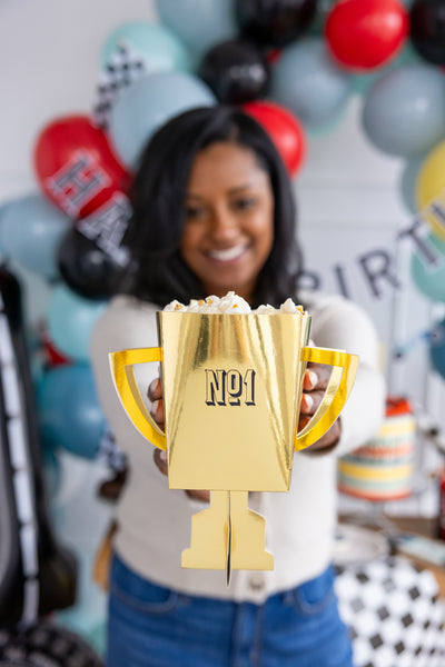 Attractive girl holding the trophy cup party favor that can be filled with racecar themed  treats