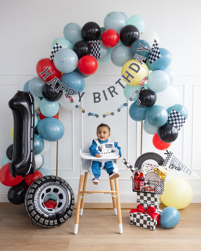 A photo booth set up featuring all of the race car decorations and a cute picture of a baby in the middle